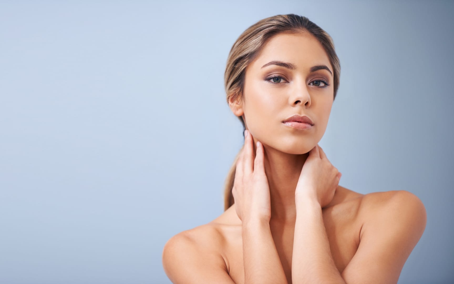 Woman touching her neck, showing healthy, glowing skin