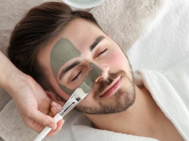 Cosmetologist applying mask on clients face in spa salon above view 1